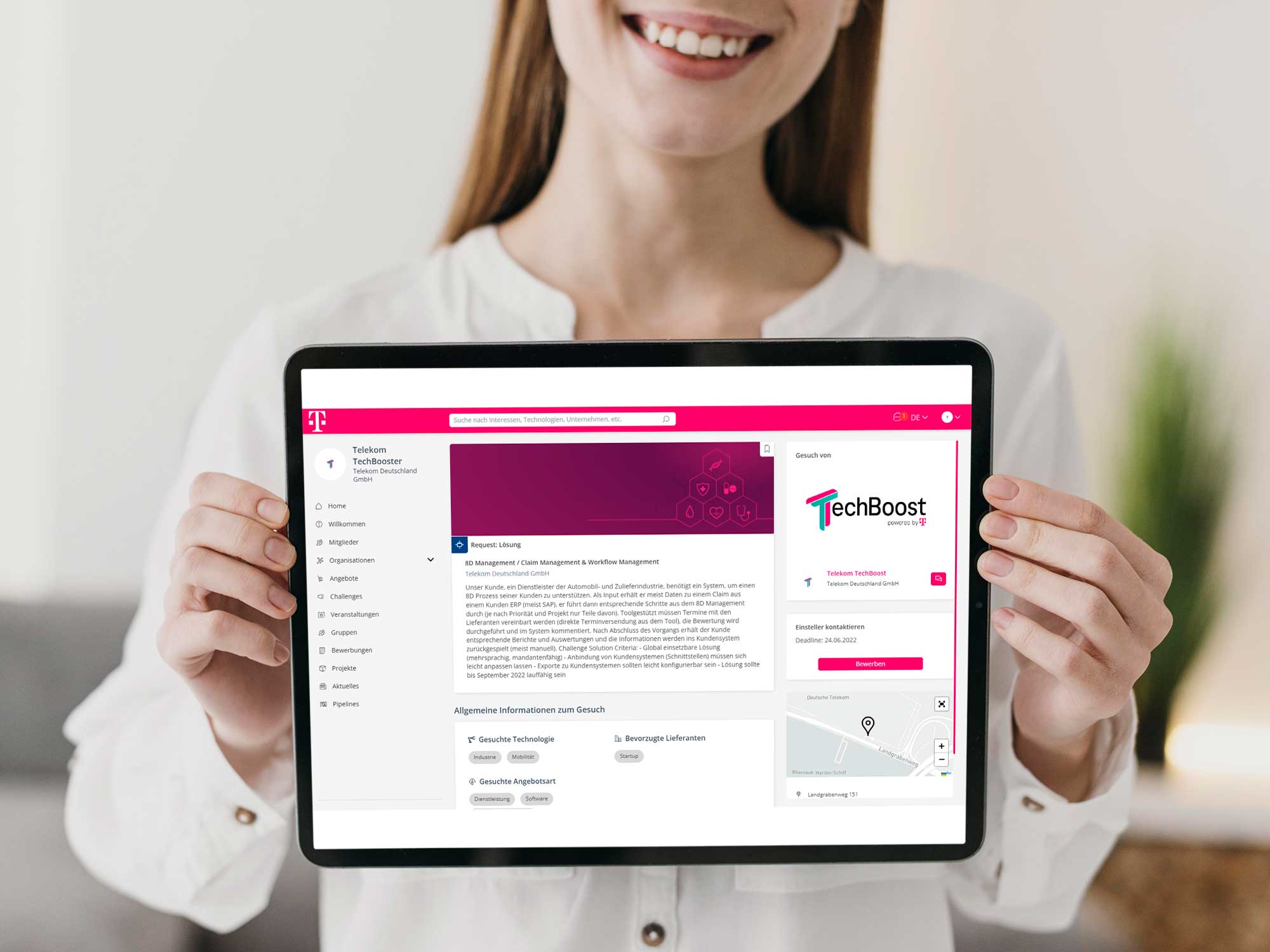 A woman presents a tablet on which the Techboost platform can be seen.